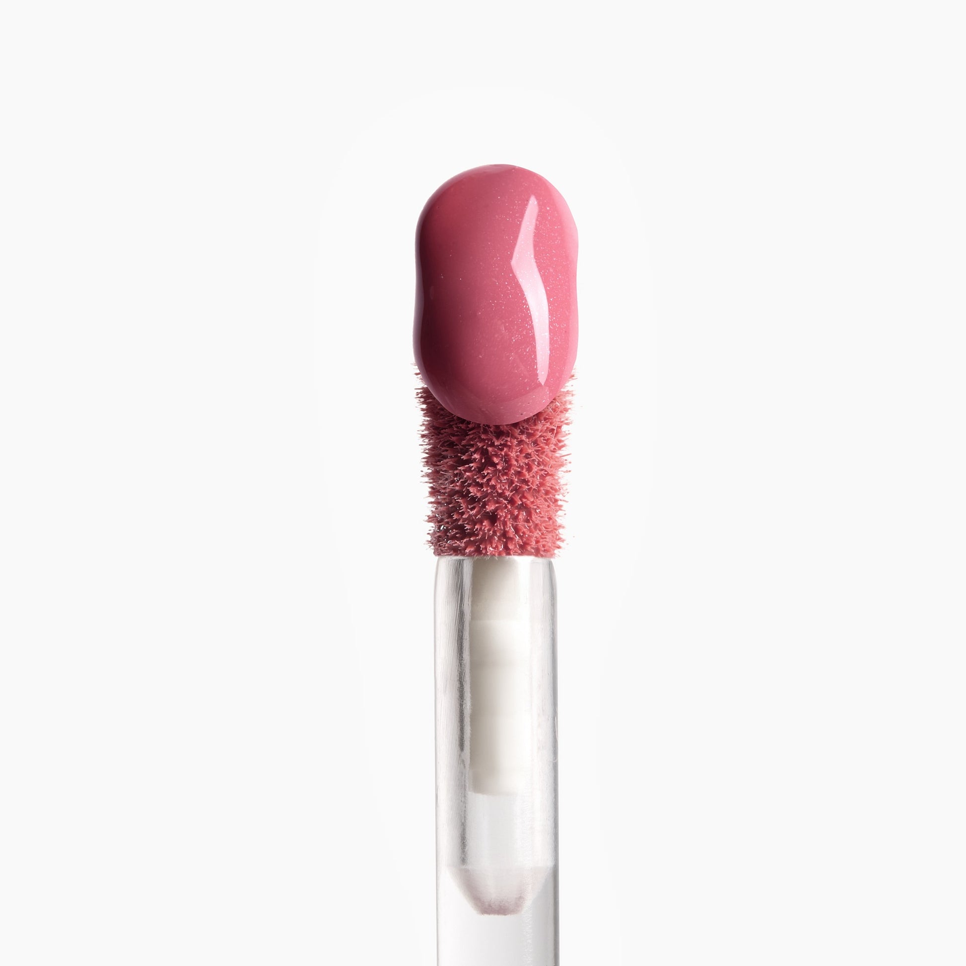 Lip gloss applicator with a pink bristle head and clear handle on a white background 