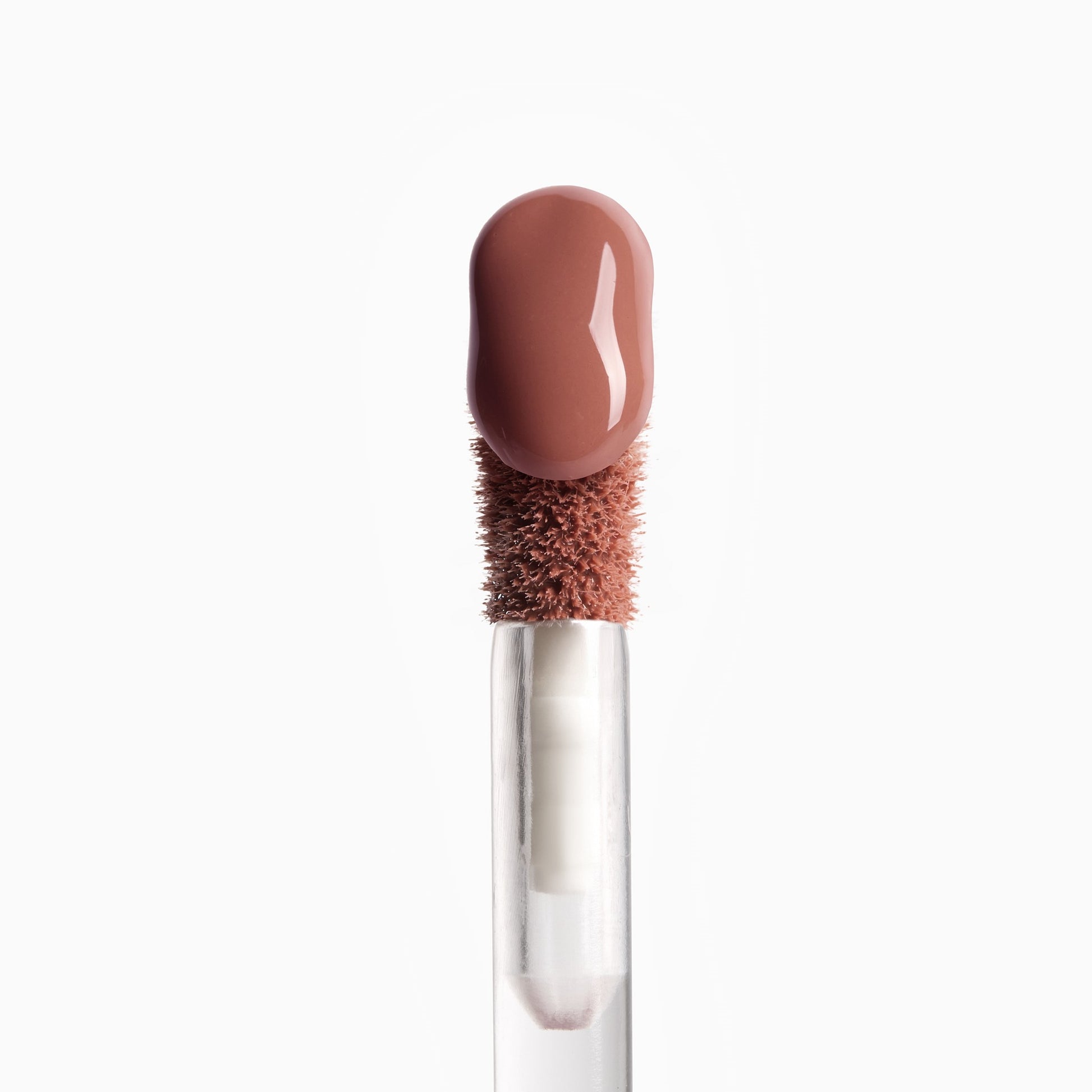 Lip gloss applicator with a brown bristle head and clear handle on a white background